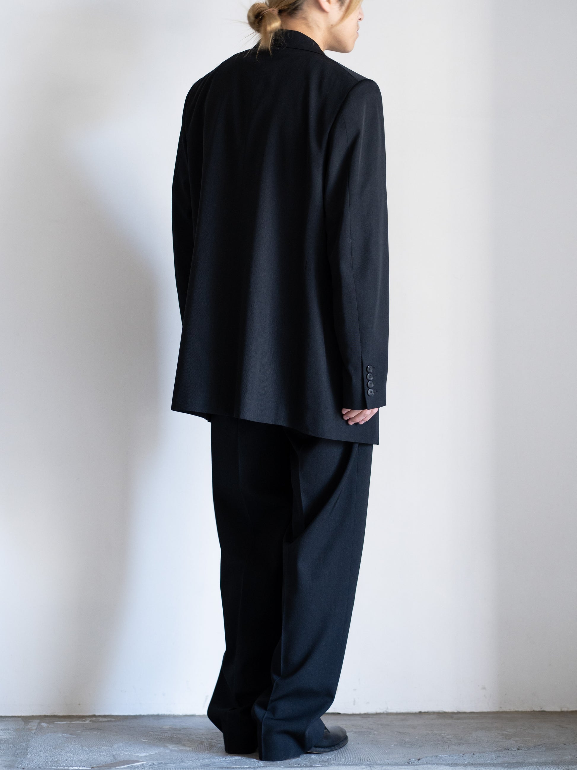 AURLEEのLIGHT WOOL MAX GABARDINE JACKETのカラーがBLACKとLIGHT WOOL MAX GABARDINE TWO-TUCK SLACKSのBLACKを着用した全身が写った背面の着用画像です。