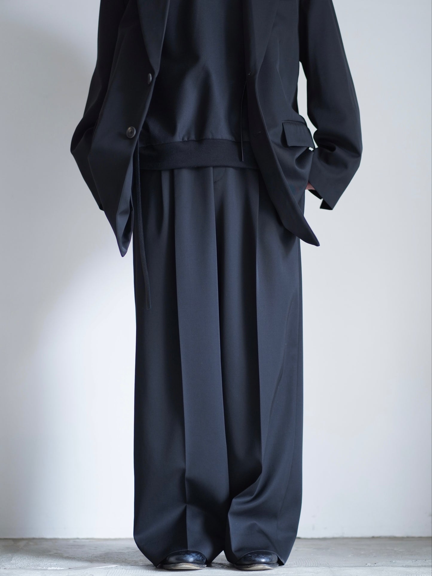 sssteinのLONG WIDE TROUSERSのカラーはBLACKのパンツの正面が写る着用画像です。こちらの商品は通信販売で購入可能です。