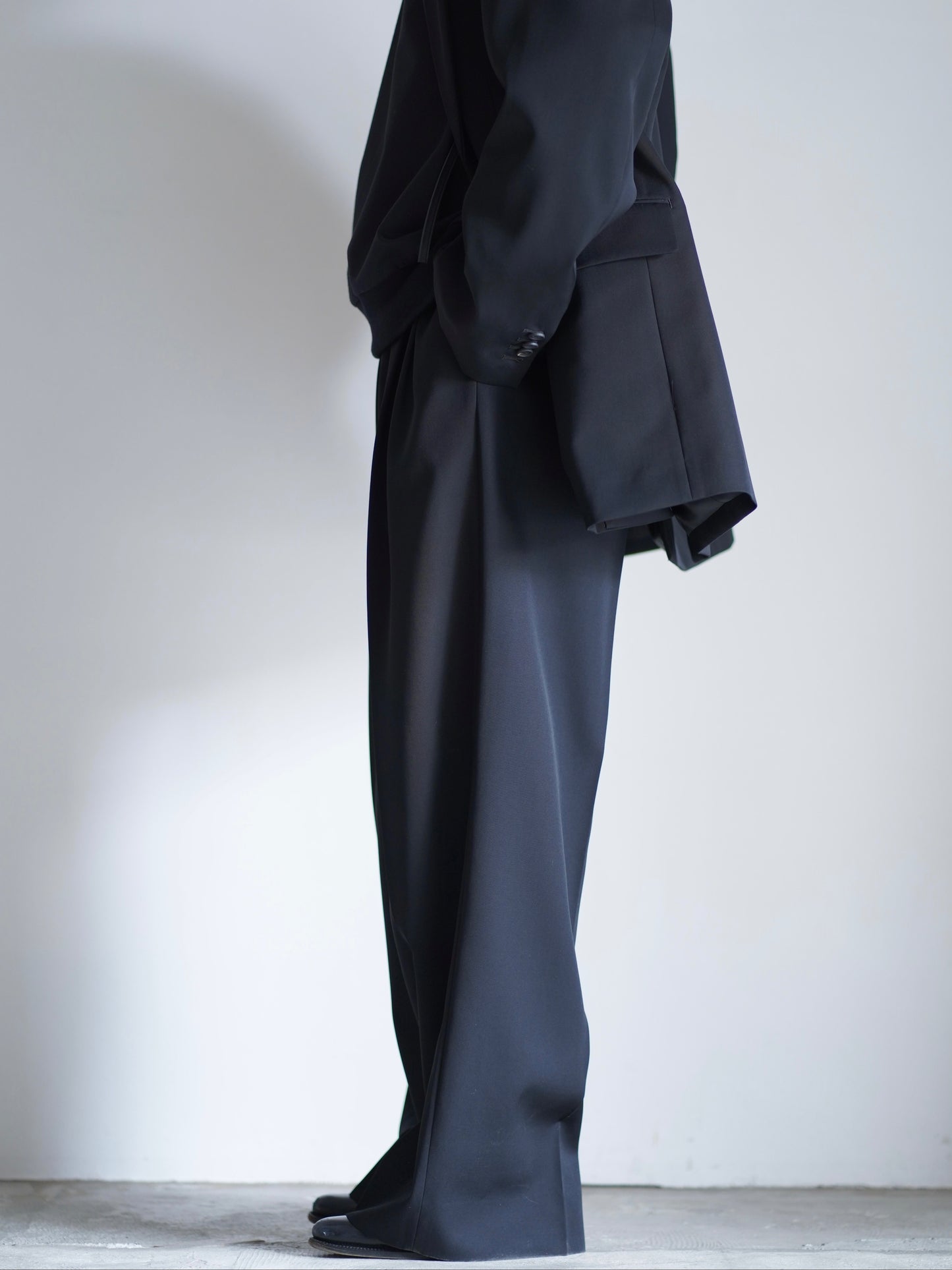 sssteinのLONG WIDE TROUSERSのカラーはBLACKのパンツの横向きの着用画像です。こちらの商品は通信販売で購入可能です。