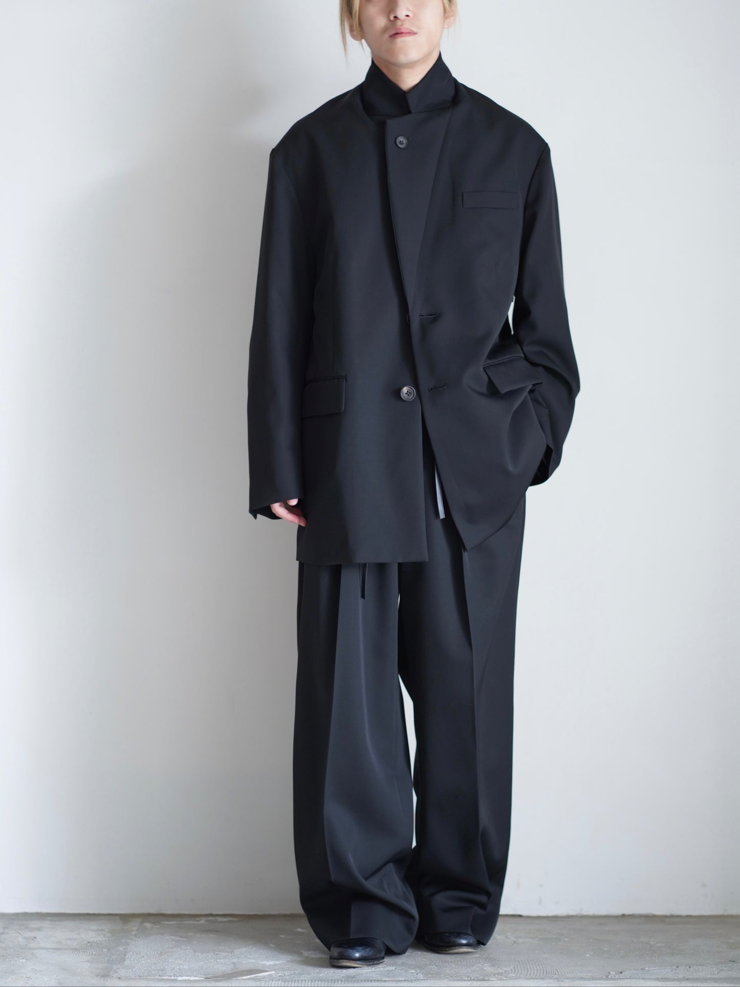 sssteinのOVERSIZED SINGLE BREASTED LONG JACKETのカラーはBLACKの襟を立てて着用した際の全身が写った着用画像です。こちらの商品は通販での購入が可能です。
