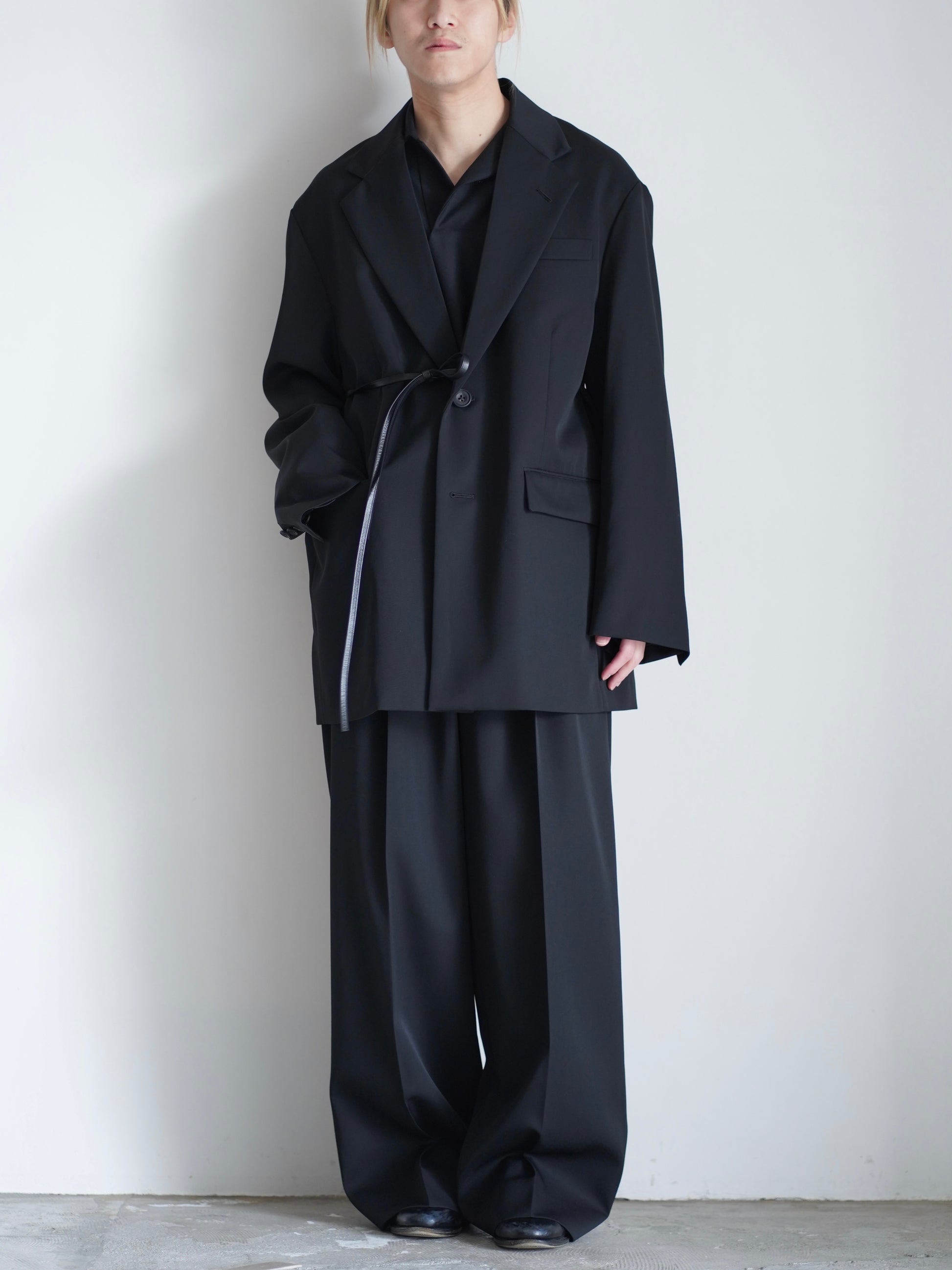 sssteinのOVERSIZED SINGLE BREASTED LONG JACKETのカラーはBLACKのレザーコードでウエストを結んで着用した際の全身が写った着用画像です。こちらの商品は通販での購入が可能です。