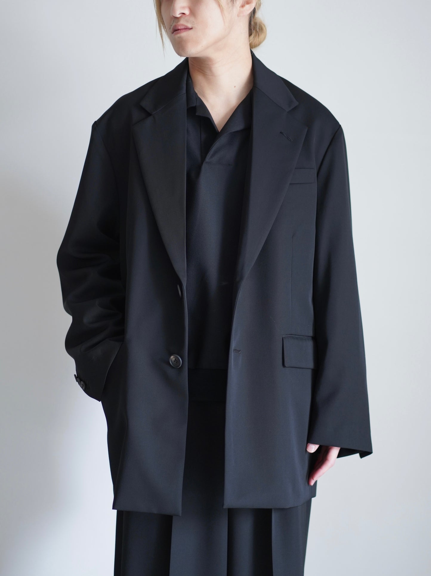 sssteinのOVERSIZED SINGLE BREASTED LONG JACKETのカラーはBLACKのボタンを外して着ているトップスの着用画像です。こちらの商品は通販での購入が可能です。