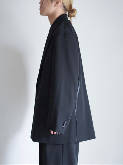 sssteinのOVERSIZED SINGLE BREASTED LONG JACKETのカラーはBLACKのトップスの横向きの着用画像です。こちらの商品は通販での購入が可能です。