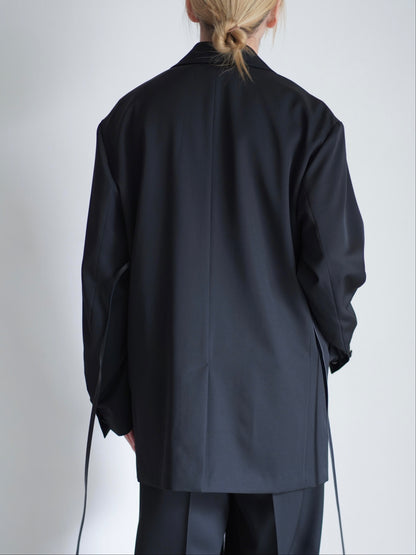sssteinのOVERSIZED SINGLE BREASTED LONG JACKETのカラーはBLACKのトップスの後向きの着用画像です。こちらの商品は通販での購入が可能です。
