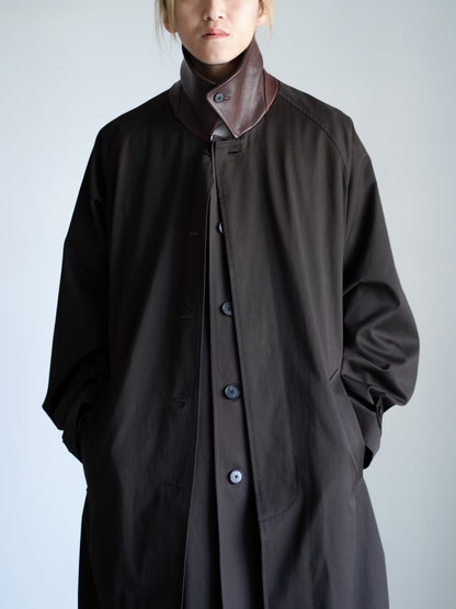 sssteinのOVERSIZED LAYERED COMBINATION COATのからーはDARK BROWNの上半身のアップで襟を立てた着用画像です。こちらは通販で購入可能です。